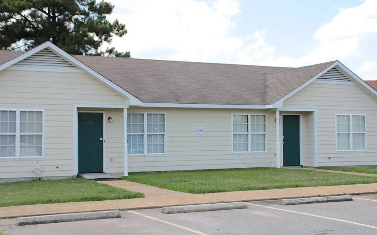 A two-story house with a green door and a driveway in front.